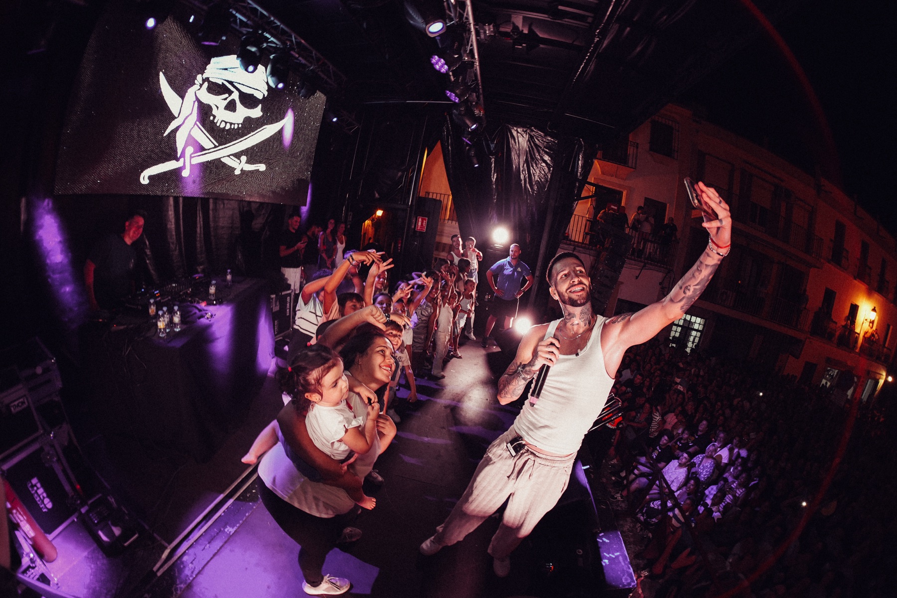 Keen Levy en un escenario junto al público, bajo luces violetas y cálidas